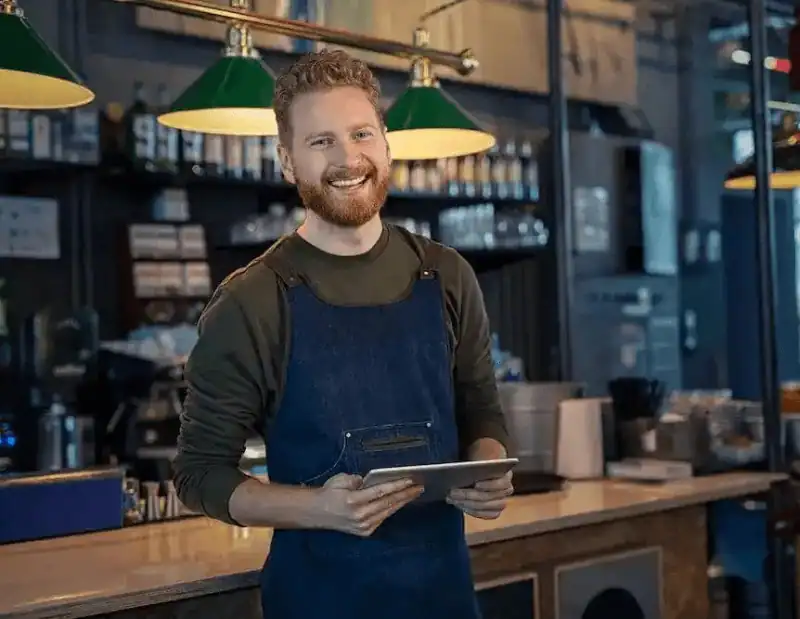 A smiling restaurant manager uses his reservation software to manage all bookings